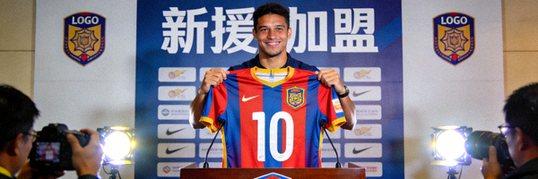 足球运动员手持新俱乐部球衣亮相转会发布会